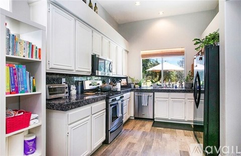 A kitchen with white cabinets and black countertops.