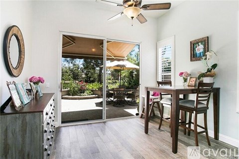 A dining room with a table and chairs and a sliding glass door.