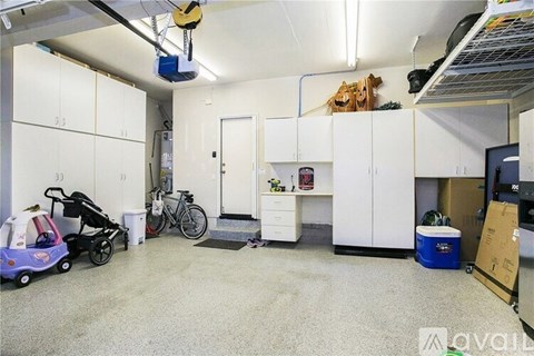 A spacious garage with a baby stroller, bicycle, and storage cabinets.