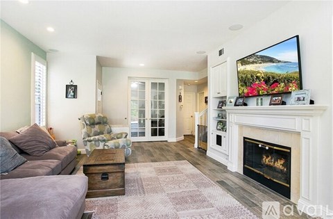 A living room with a grey couch, a coffee table, a fireplace, and a television on the wall.