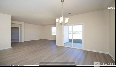A spacious room with wooden flooring and a chandelier hanging from the ceiling.