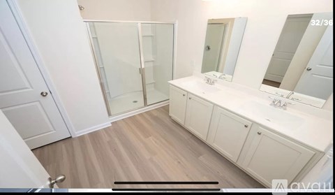 A bathroom with a walk-in shower, double sink vanity, and a white cabinet.