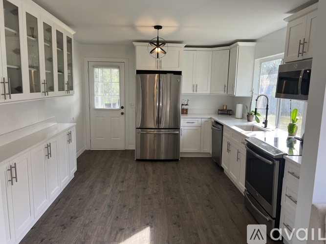 A kitchen with white cabinets and a wooden floor.