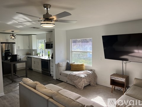 A living room with a grey couch and a ceiling fan.