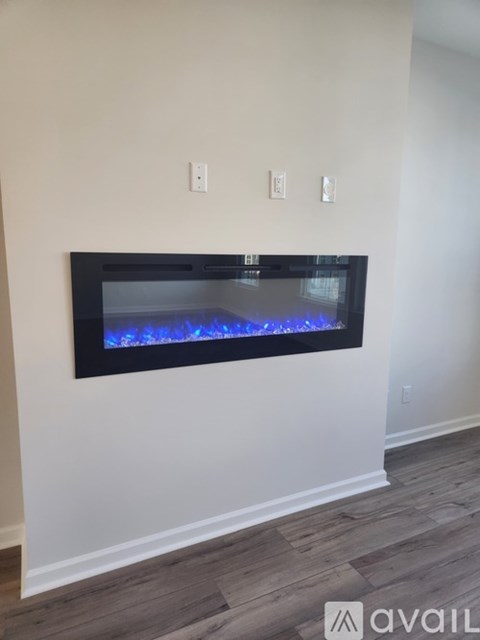 A modern fireplace with a black frame and blue flames in a living room.