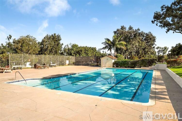 A large outdoor swimming pool surrounded by a fence and trees.