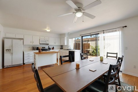 A kitchen with a table and chairs in the foreground and a refrigerator, microwave, and oven in the background.