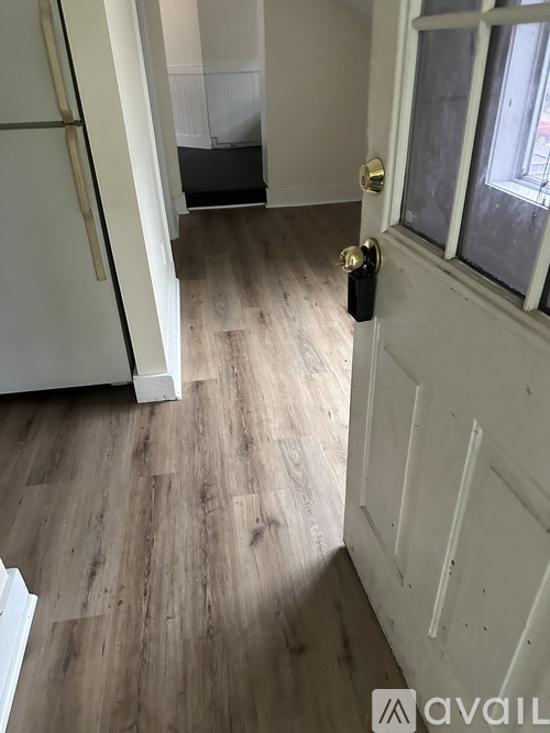 A white door with a gold handle is open to a hallway.