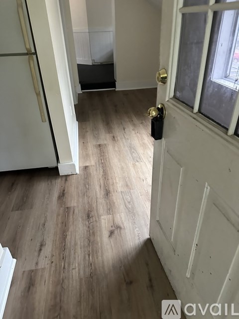 A white door with a gold handle is open to a hallway.