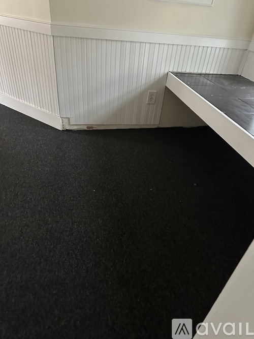 A room with a black carpet and a white wall.