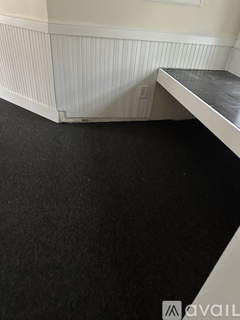 A room with a black carpet and a white wall.