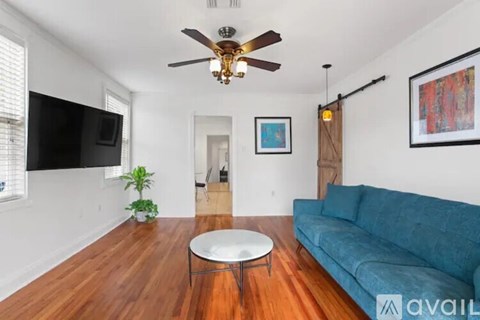 A living room with a blue couch and a ceiling fan.