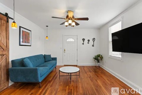 A living room with a blue couch and a ceiling fan.