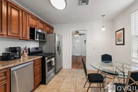 A kitchen with brown cabinets and a glass table.