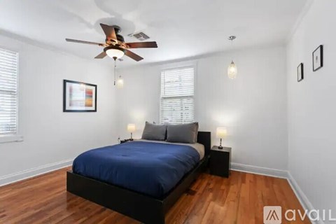 A bedroom with a bed, two lamps, and a ceiling fan.