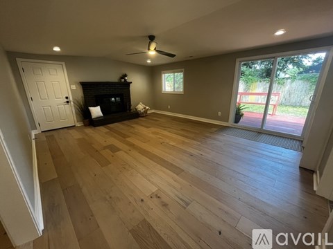 A spacious room with wooden flooring and a fireplace.