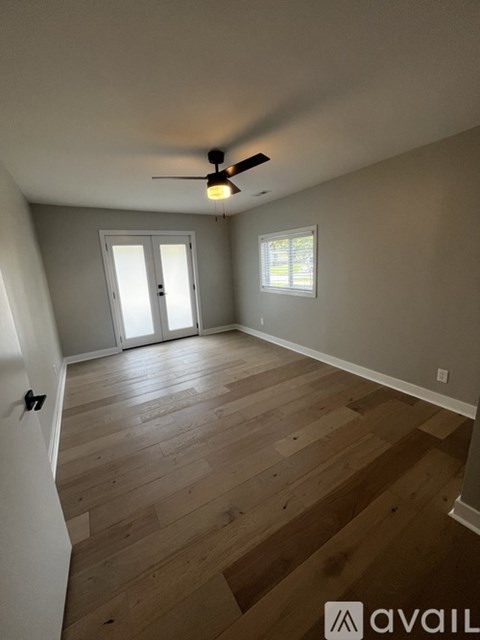 A room with a ceiling fan and wooden flooring.