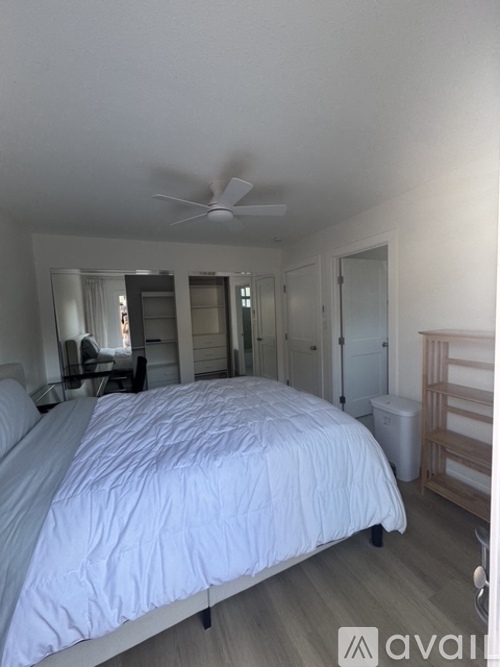 A bedroom with a large bed and a ceiling fan.