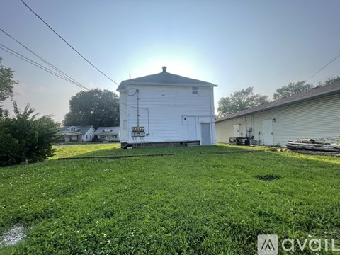 A white barn sits in a grassy field with a clear sky above.