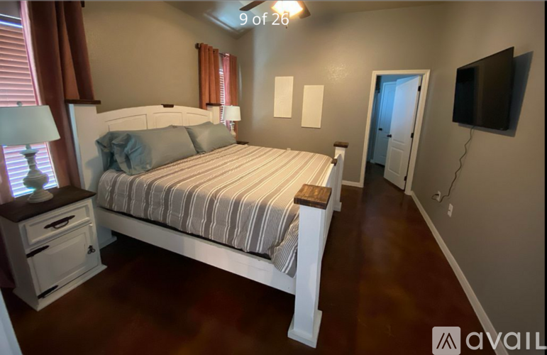 A bedroom with a large bed and a television on the wall.