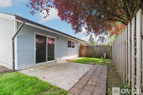 A backyard with a fence and a tree with red leaves.