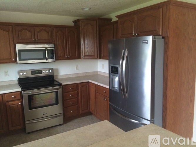 A kitchen with wooden cabinets and a stainless steel refrigerator.