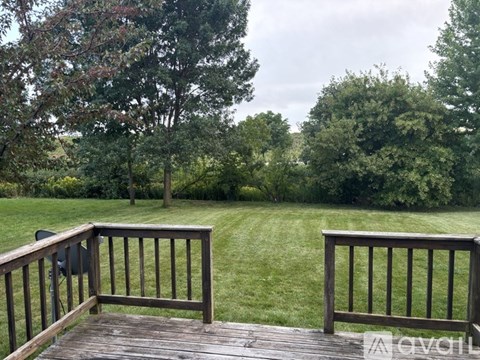 A wooden deck with a railing overlooking a grassy area.