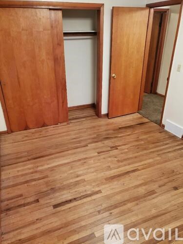A room with wooden floors and two open doors.