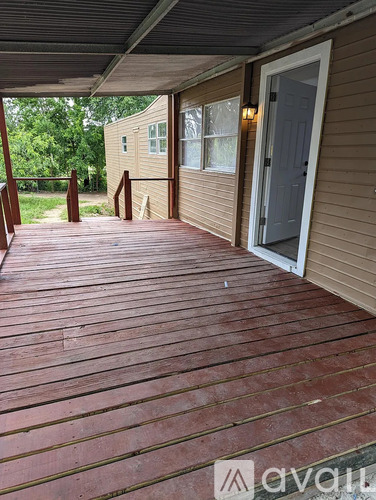 A wooden deck with a door and windows leading to a house.
