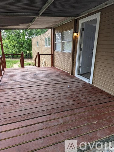 A wooden deck with a door and windows leading to a house.