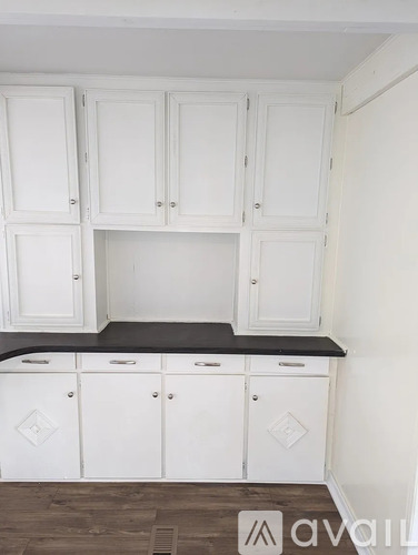 A kitchen with white cabinets and a black countertop.