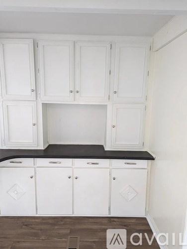 A kitchen with white cabinets and a black countertop.
