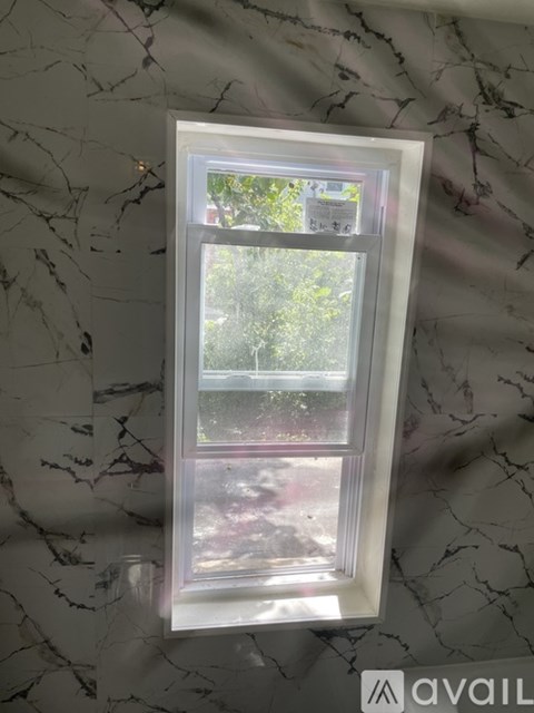 A window with a white frame is installed in a marble wall.