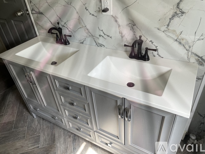 A bathroom vanity with two sinks and a marble backsplash.