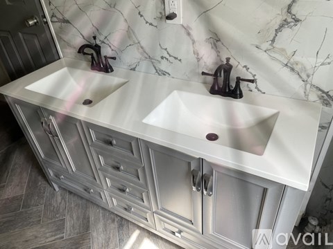 A bathroom vanity with two sinks and a marble backsplash.