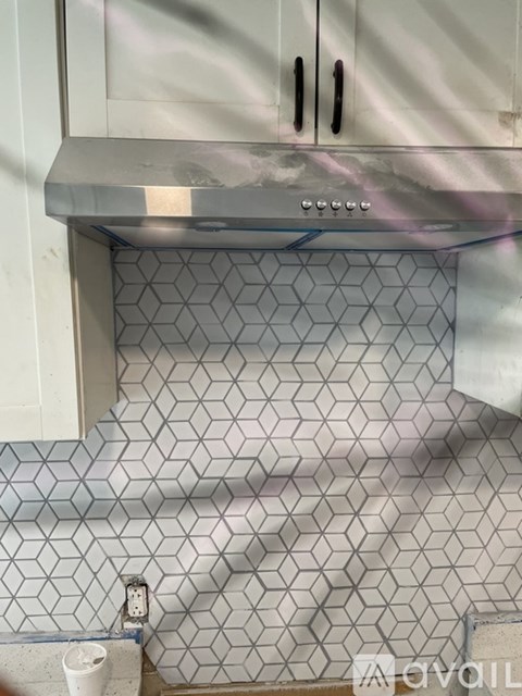 A kitchen with a stove top oven and a tile backsplash.