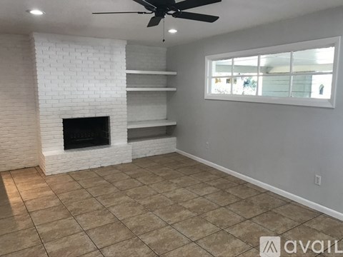 A living room with a fireplace and a ceiling fan.
