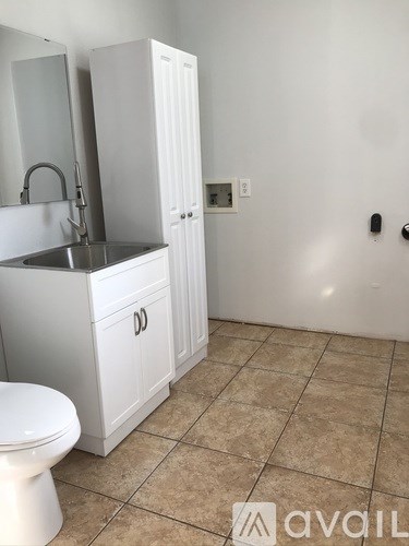A bathroom with a toilet, sink, and cabinet.
