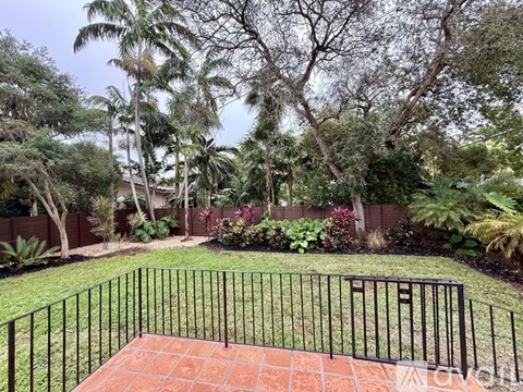 A backyard with a black fence and a brick patio.