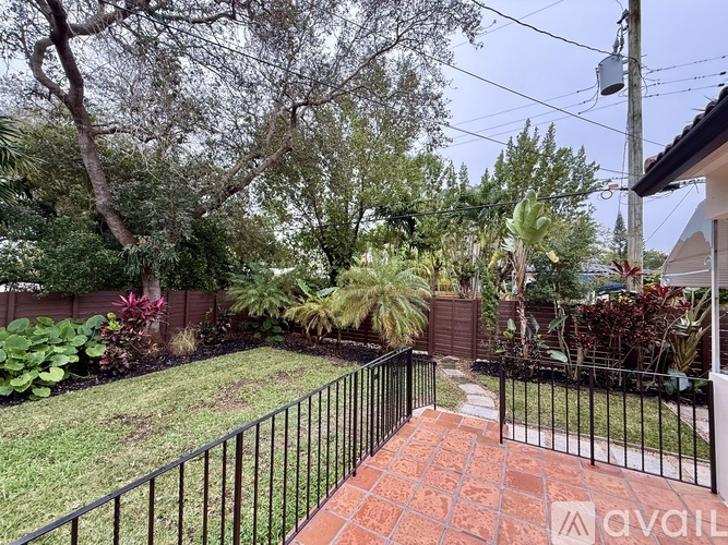 A backyard with a black fence and a brick pathway.