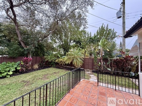 A backyard with a black fence and a brick pathway.