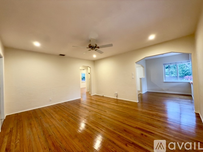 A spacious room with wooden floors and a ceiling fan.