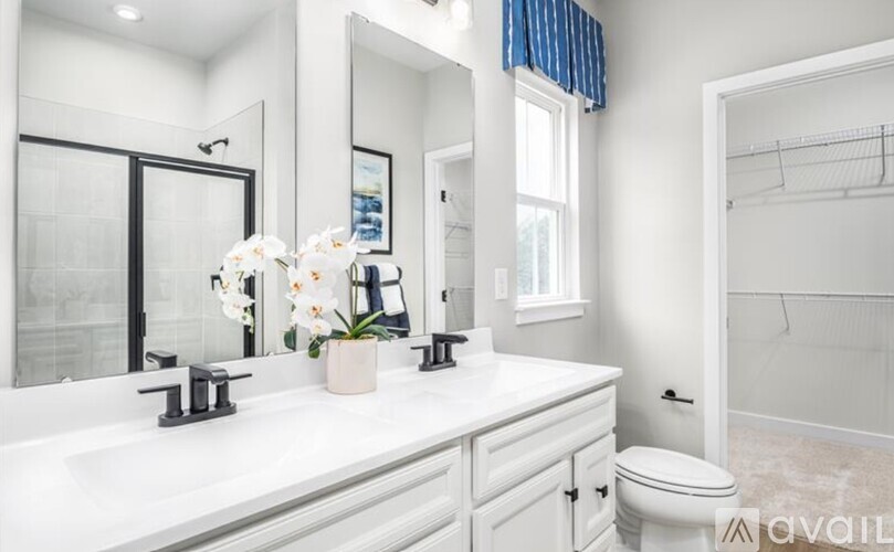 A white bathroom with a toilet, sink, and mirror.