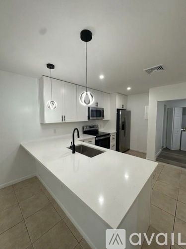 A modern kitchen with a white countertop and a black refrigerator.