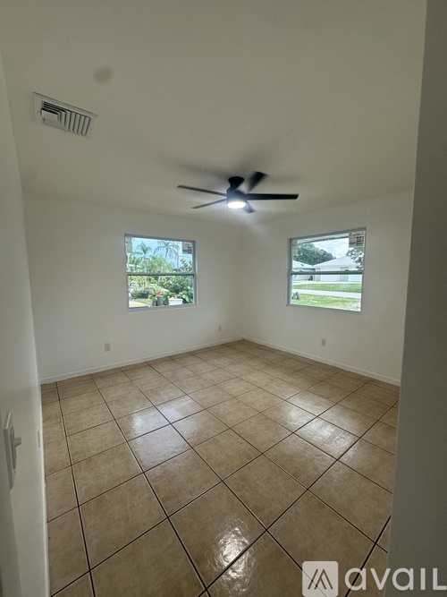 A room with a ceiling fan and two windows.
