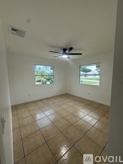 A room with a ceiling fan and two windows.