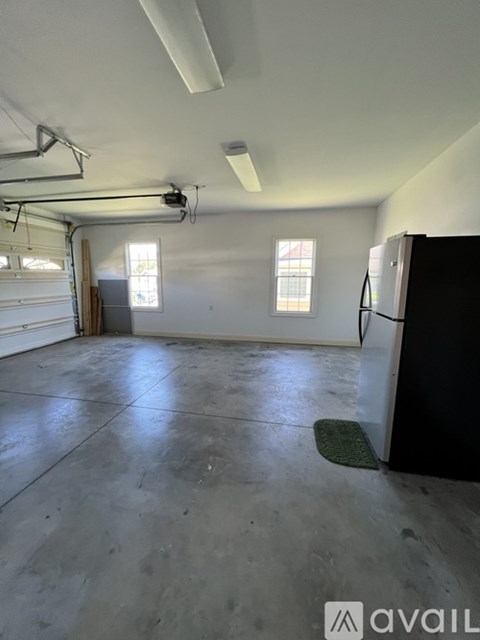 A large empty room with a black refrigerator on the right side.