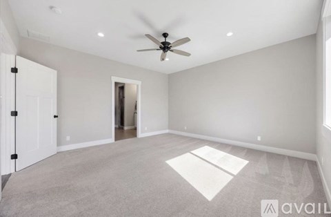 A spacious room with a ceiling fan and a rug on the floor.