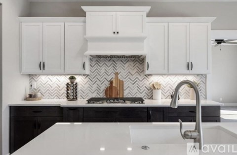 A kitchen with white cabinets and a black and white tiled backsplash.