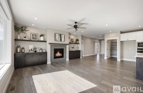 A spacious living room with a fireplace and a ceiling fan.
